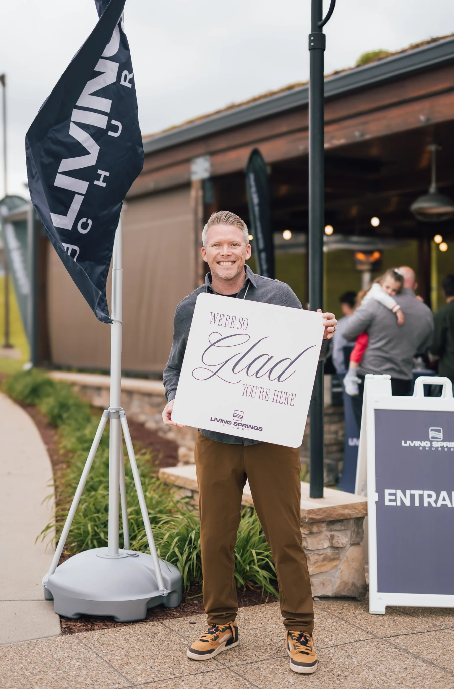 A man holding a Glad You’re Here sign by the entrance