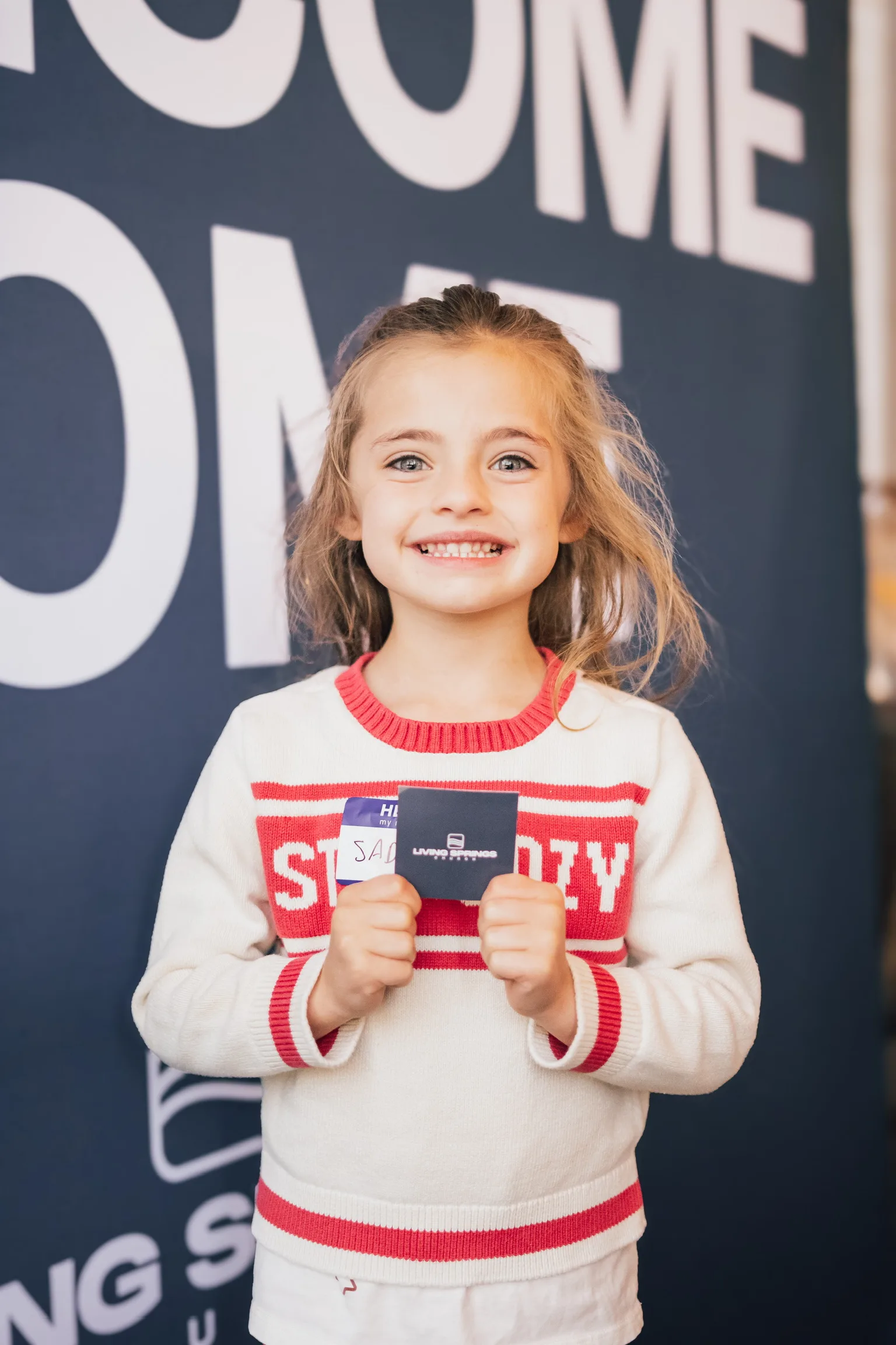 A girl holding a Living Springs name card