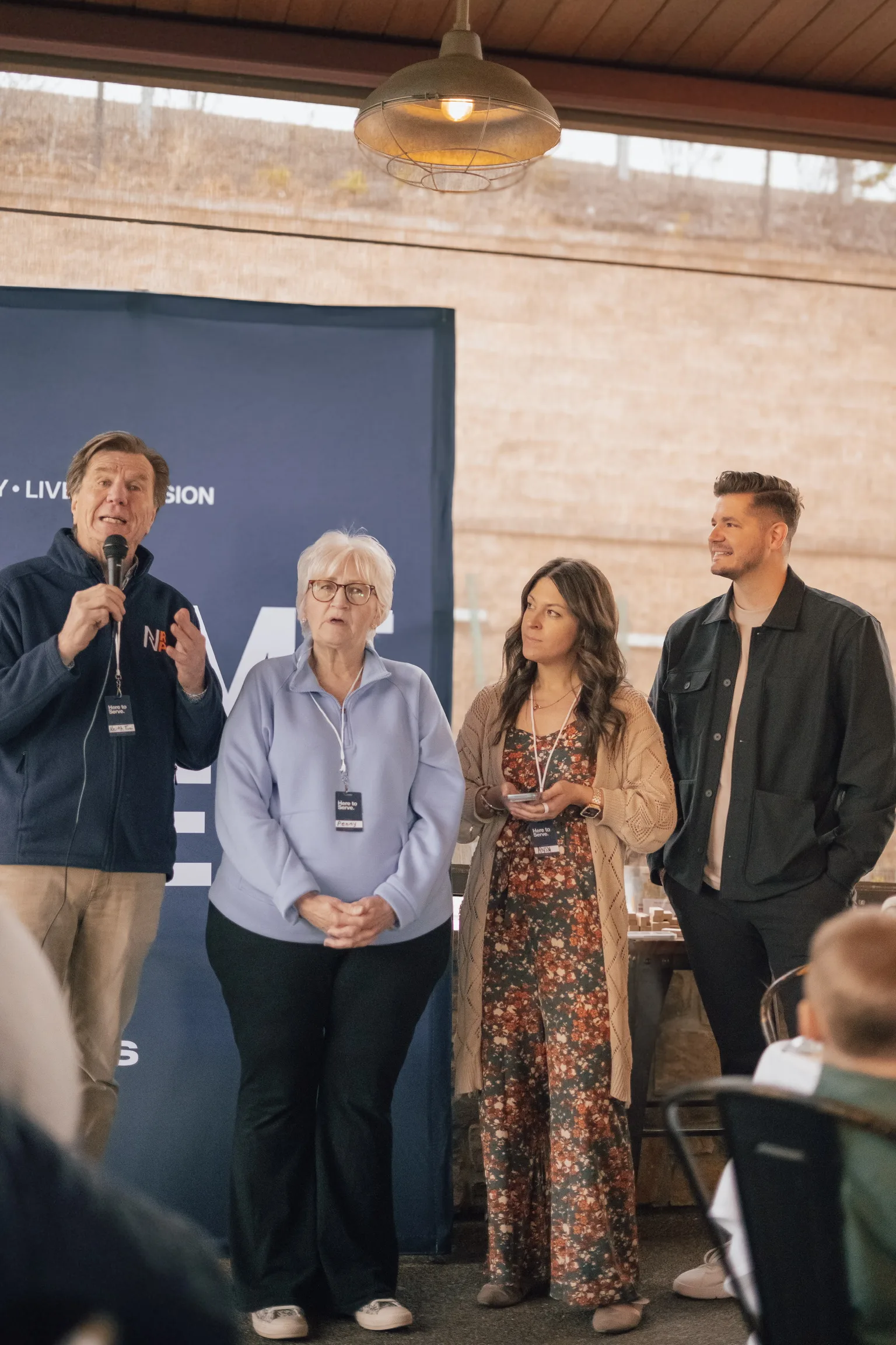 Four people speaking at the Welcome and mission backdrop