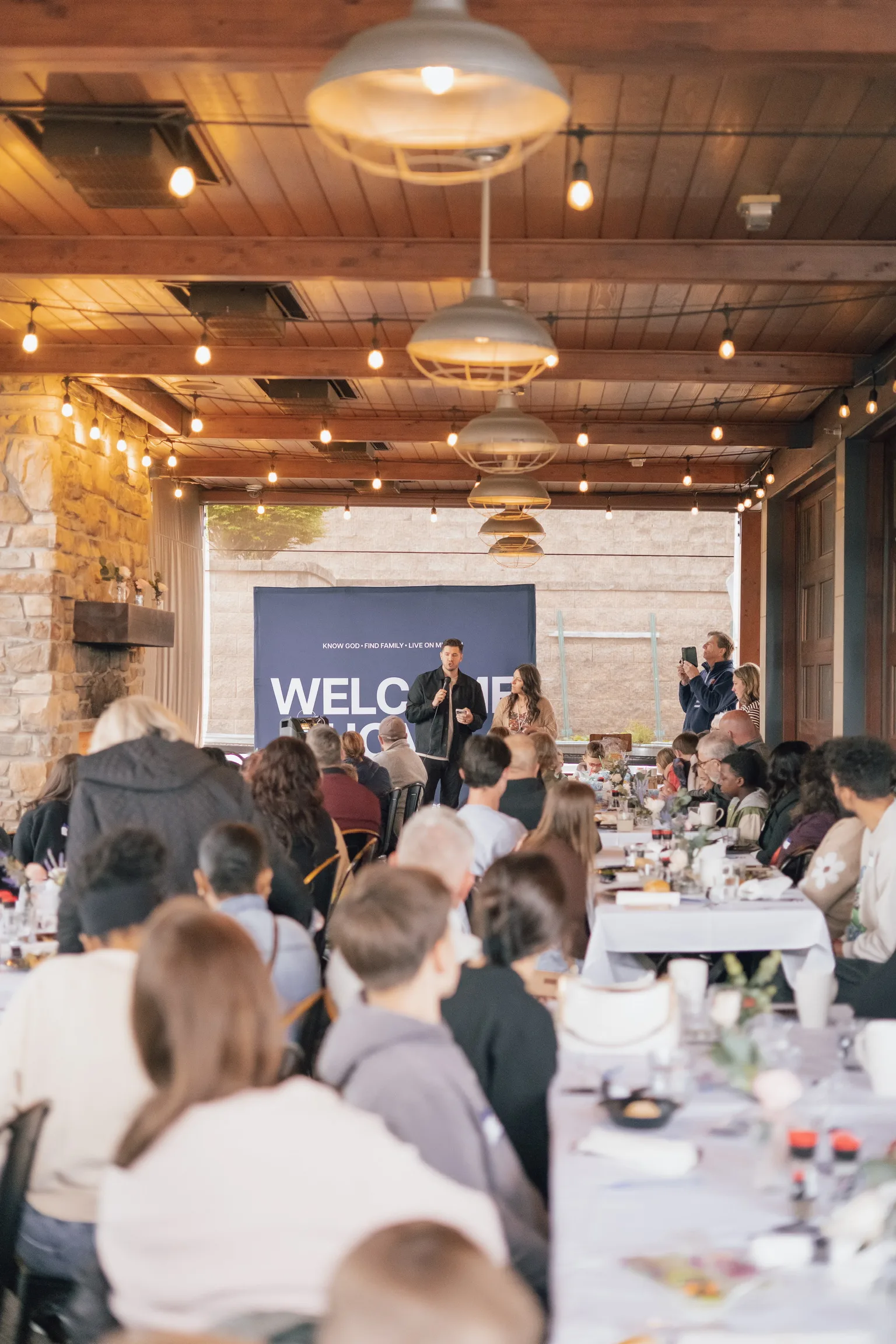 A couple speaking with a microphone at the Welcome backdrop