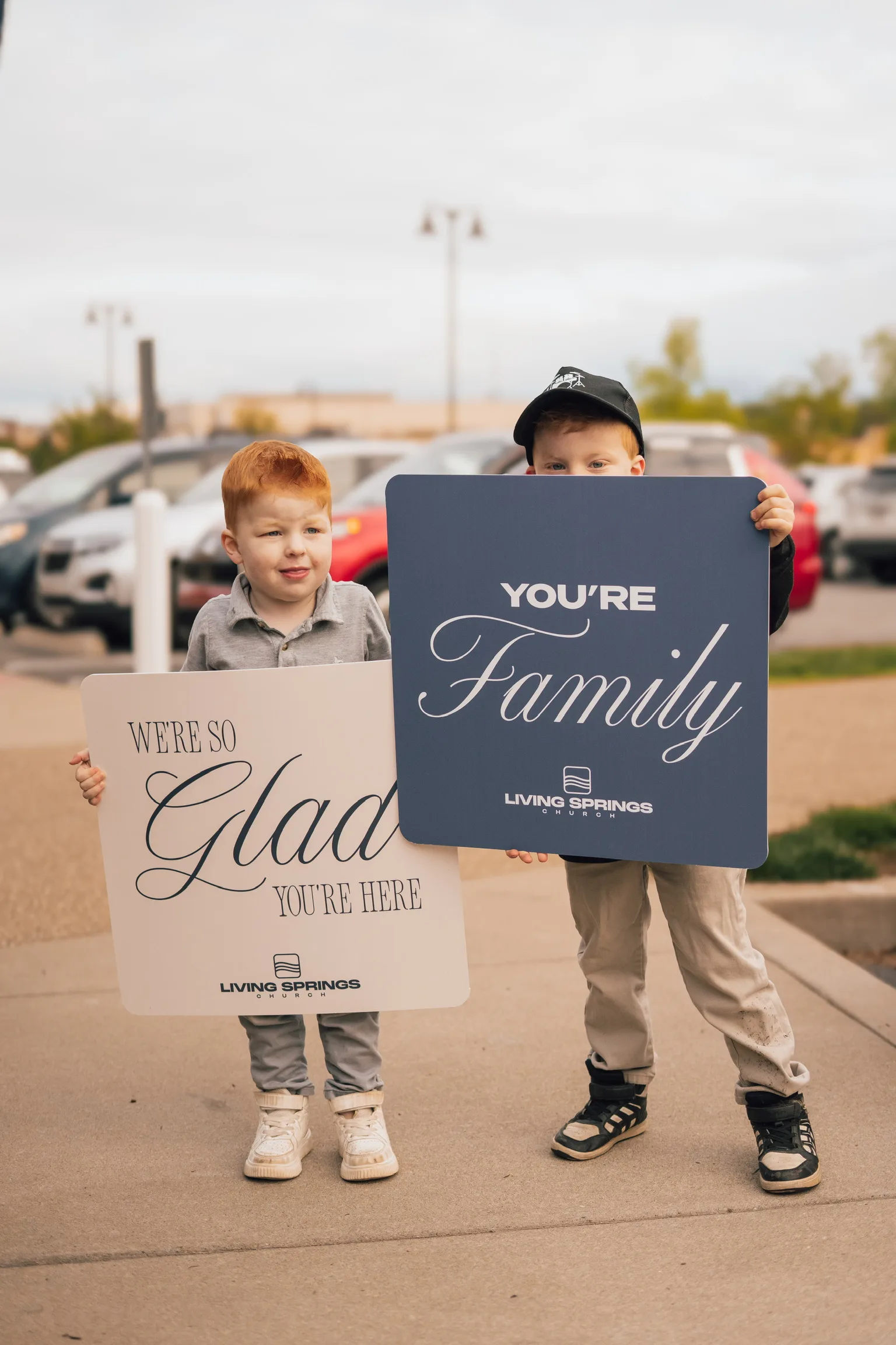 Two boys holding Glad You’re Here and You’re Family signs