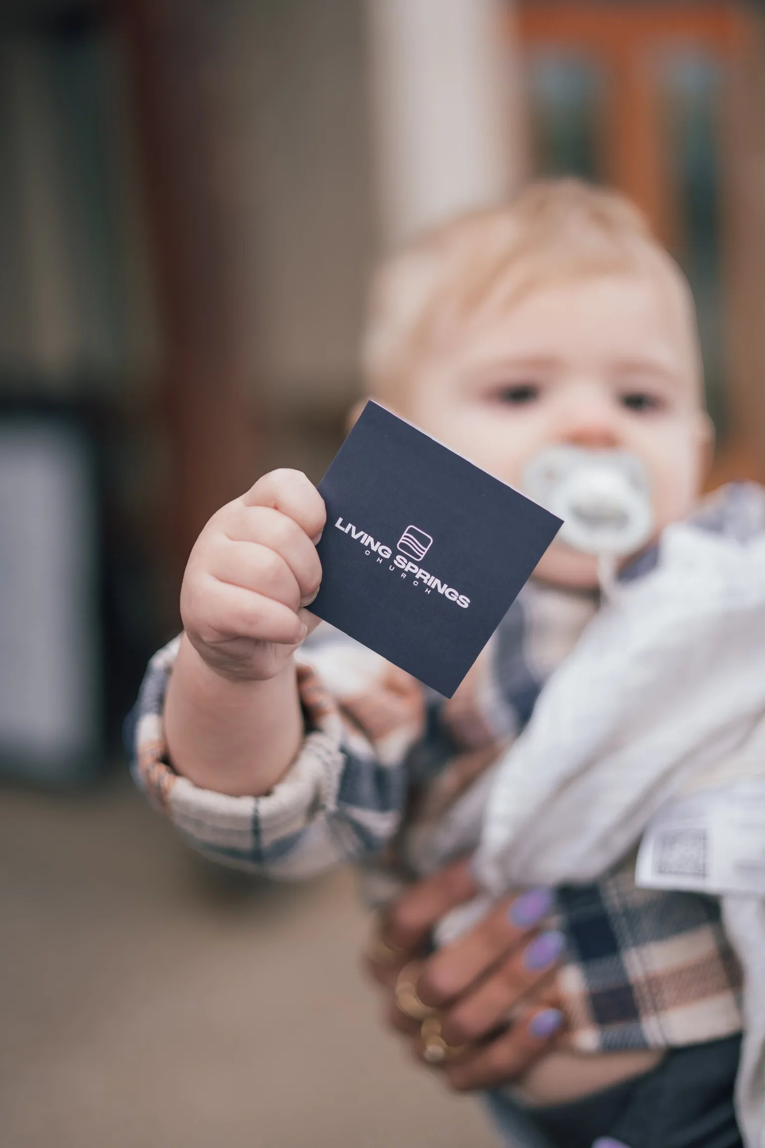 A toddler and an adult holding a Living Springs card
