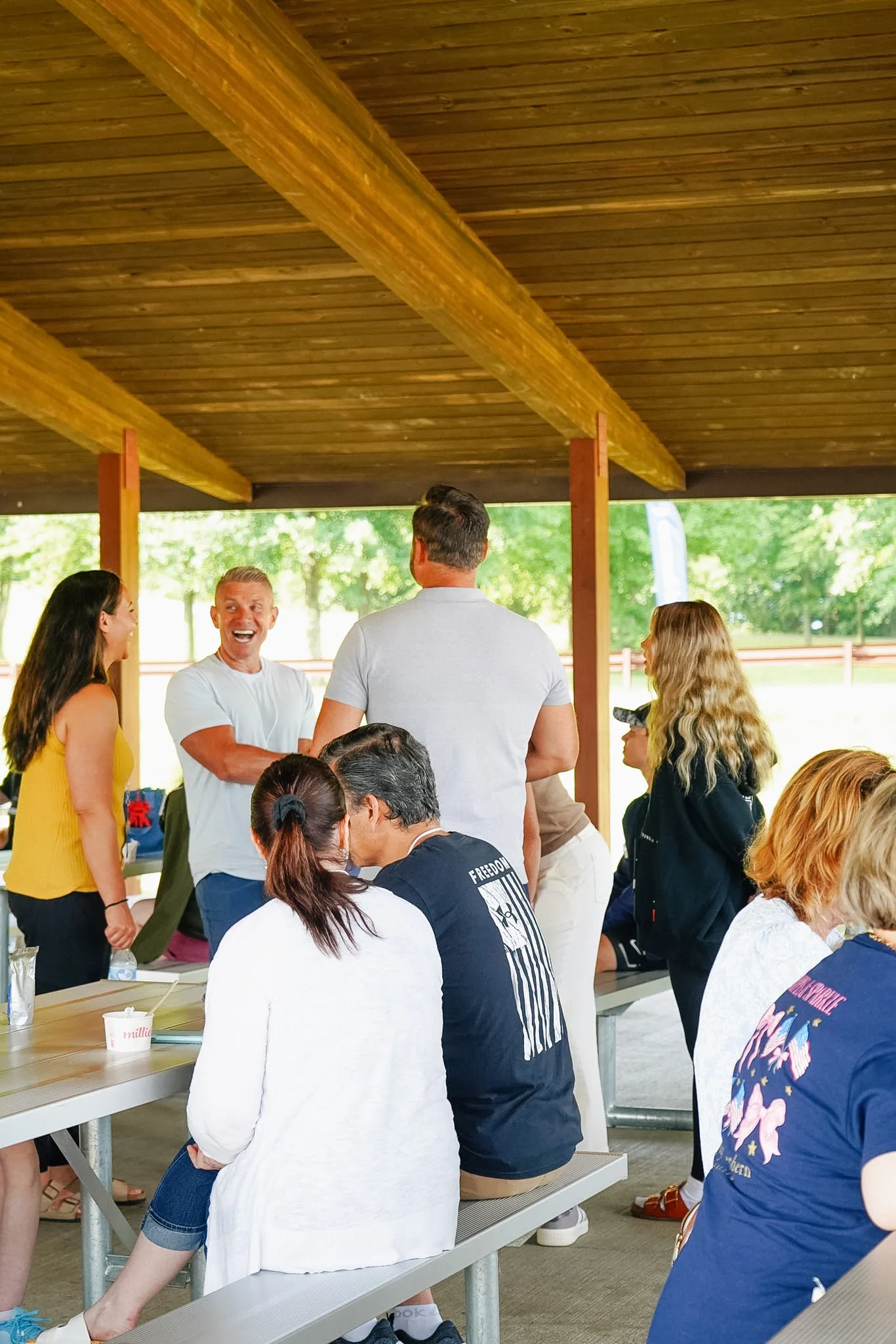 A multi-generation group talking under an outdoor pavilion